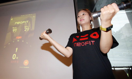 25일 서울 광화문 센터포인트빌딩의 한 식당에서 열린 KT 퓨처 포럼에서 한 관계자가 피트니스 밴드 '네오핏'을 시연하고 있다.  연합뉴스